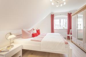 a white bedroom with a white bed and red pillows at Haus Eichenwald in Glowe