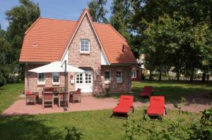 a house with chairs and a table and an umbrella at Haus Eichenwald in Glowe
