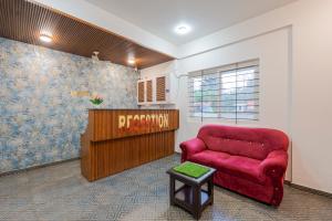 a waiting area with a red couch in a room at Hotel Royal Manyata in Bangalore