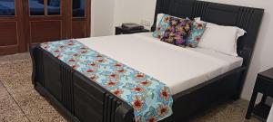 a bed with a black head board with a floral blanket at TheChef NungwiBungalow in Kidoti