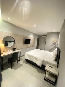 a bedroom with a bed and a desk and a television at MBS HOTEL Medan in Medan