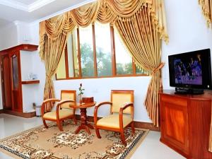 uma sala de estar com mesa, cadeiras e uma TV em Vy Chhe Hotel em Battambang