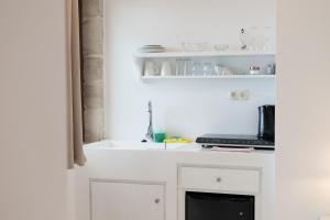 Una cocina con gabinetes blancos y un fregadero. en Elia, en Kavoúsion 132 fotos más