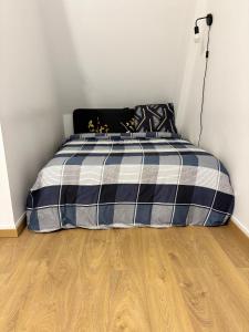 a bedroom with a bed with a blue and white plaid blanket at Super appartement in Malesherbes