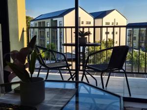 a balcony with two chairs and a table with a plant at Charming Oasis in the East in Boksburg