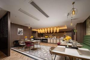 a living room with tables and chairs and a kitchen at Jinjiang Metropolo Hotel - Taizhou Wanda Plaza in Taizhou