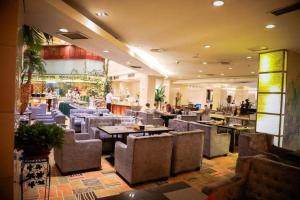 um restaurante com mesas e cadeiras e pessoas nele em Tianjin Juchuan Lily Hotel em Binhai
