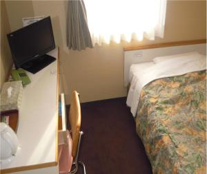 a hotel room with a bed and a flat screen tv at Niigata Park Hotel in Niigata
