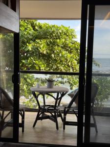 een tafel en stoelen op een balkon met uitzicht op de oceaan bij Bonbon Beach House in Liloan +30 foto's