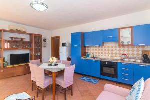 uma cozinha com armários azuis e uma mesa com cadeiras em Pupureddu con Terrazza ad Olbia em Olbia