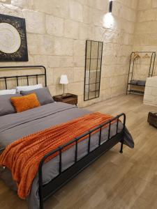 Un dormitorio con una cama con una manta naranja. en Vittoria - charming 500-year-old house nestled within the fortified walls of Birgu, en Birgu