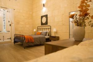 Un dormitorio con una cama y un jarrón de flores. en Vittoria - charming 500-year-old house nestled within the fortified walls of Birgu, en Birgu
