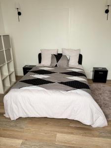 a bed with black and white sheets and pillows at Super appartement in Malesherbes