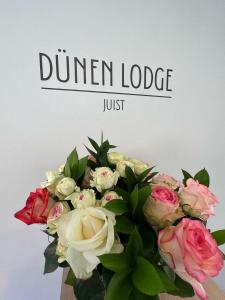 于斯德Dünen Lodge 4的一瓶鲜花，上面写着“晚餐旅馆”