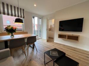 于斯德Dünen Lodge 3的客厅配有桌子和墙上的电视 更多2张照片