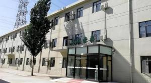 ein weißes Gebäude mit einem Baum davor in der Unterkunft GreenTree Inn Express Cangzhou Yunhe District Mingzhu Market in Cangzhou