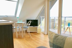 un salon avec une table, des chaises et une télévision dans l'établissement Strandhaus Rose, à Juist