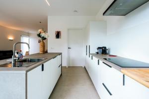 a kitchen with white cabinets and a sink at Bocca in Hasselt