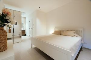 a white bedroom with a large bed and a vase with flowers at Bocca in Hasselt