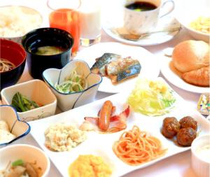 einen Tisch mit Teller mit Lebensmitteln und Schüsseln mit Lebensmitteln in der Unterkunft Niigata Park Hotel in Niigata