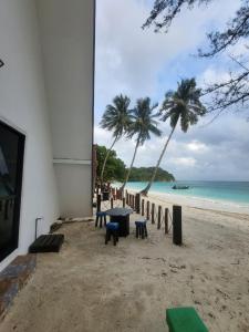 a table and chairs on a beach with the ocean at DEWATI ROOMSTAY B&B in Lang Tengah