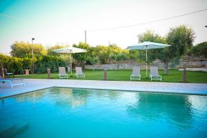 una piscina con due sedie e due ombrelloni di Villa Ostuni a Monopoli Altre 29 foto