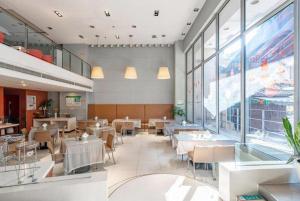 Jinjiang Inn Hangzhou Xihu Avenue Branch في هانغتشو: مطعم به طاولات وكراسي ونوافذ