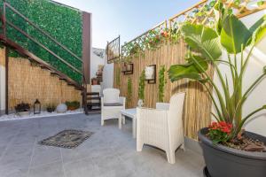 um pátio com cadeiras brancas, uma mesa e uma planta em Msuite em Giarre