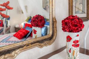 dwie wazy wypełnione czerwonymi różami przed lustrem w obiekcie Oasi di pace we Florencji