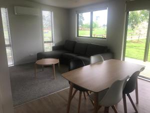 ein Wohnzimmer mit einem Tisch und einem Sofa in der Unterkunft Country Cottage Centrally Located in Tauwhare