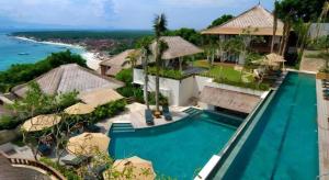 Batu Karang Lembongan Resort & Spa في نوسا ليمبونغان: منظر جوي لمنتجع به حمام سباحة والمحيط