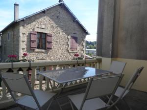 una mesa y sillas en un balcón con un edificio en La Petite Cerise, en Eymoutiers