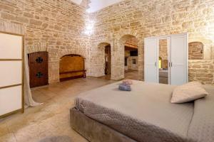 Un dormitorio con una cama grande en una pared de piedra. en Apulia Luxury House, en Toritto