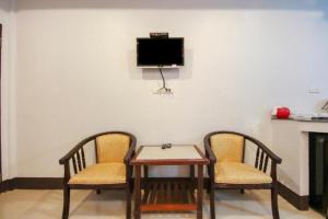 duas cadeiras e uma mesa e uma televisão na parede em OYO 75310 Canalis Resort em Khao Lak