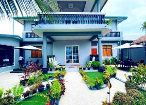 a house with a balcony and a courtyard with plants at Ekefaru Inn in Viligili