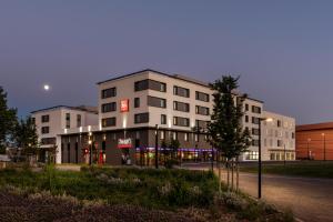 un bâtiment blanc avec un panneau sur son côté dans l'établissement ibis budget Saint Quentin Yvelines - Vélodrome, à Montigny-le-Bretonneux