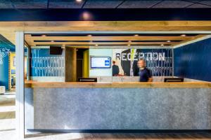 a man sitting at a bar in a restaurant at ibis budget Saint Quentin Yvelines - Vélodrome in Montigny-le-Bretonneux