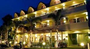 a building with palm trees in front of it at night at Wild Orchid Villa Krabi in Ao Nam Mao
