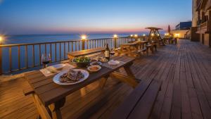 Una terraza de madera con una mesa con comida y vino. en Youngduk Sea & Spa Pension, en Yŏngdŏk