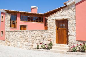 una casa rosa con una puerta de madera y flores en Casal Frias, en Barreira