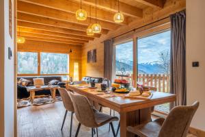 a dining room with a table and chairs and a large window at Chalet cosy et neuf, Grande Terrasse, Vue panoramique in Saint-Jean-de-Sixt