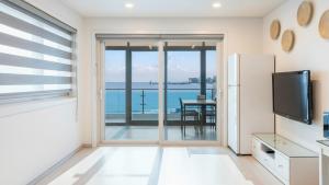 a living room with a refrigerator and a view of the ocean at Goseong Badasga per Osyeonbyu Pension in Goseong