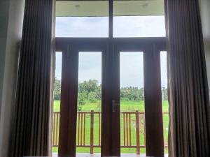 een raam met uitzicht op een tuin bij Paddy Edge Ahangama in Ahangama