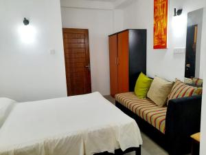a bedroom with a bed and a couch in it at Tusker Home stay in Sri Jayewardenepura Kotte