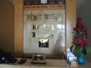Un escritorio con un cartel de hotel y un jarrón de flores. en Binh Hung Hotel, en Ho Chi Minh