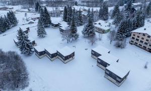 ein schneebedecktes Dorf mit Bäumen und Gebäuden in der Unterkunft Résidence Vacancéole Les Monts Jura in Lélex