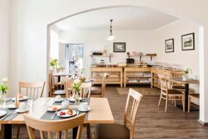 a dining room with tables and chairs and a kitchen at Land-gut-Hotel Westerkrug in Wanderup