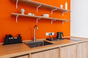 a kitchen with a sink and an orange wall at FortyPlusOne Hotel Vienna in Vienna