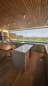 une pièce avec une table et un banc et une grande fenêtre dans l'établissement Lanai Imbassai, à Mata de São João