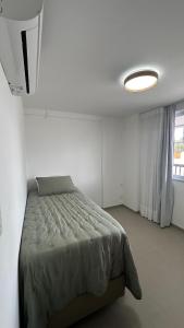 une chambre avec un lit dans une pièce blanche dans l'établissement Lanai Imbassai, à Mata de São João